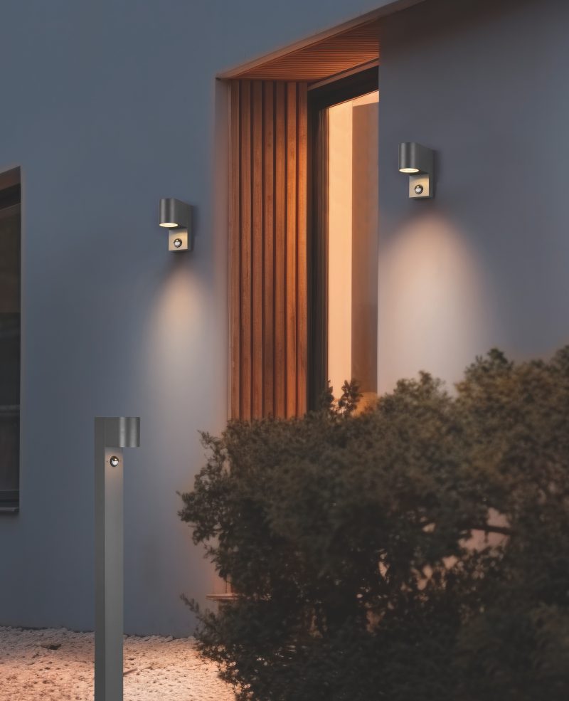 Wall lamp placed on the exterior of a building during night time with copy space. Modern electrical equipment for illumination.