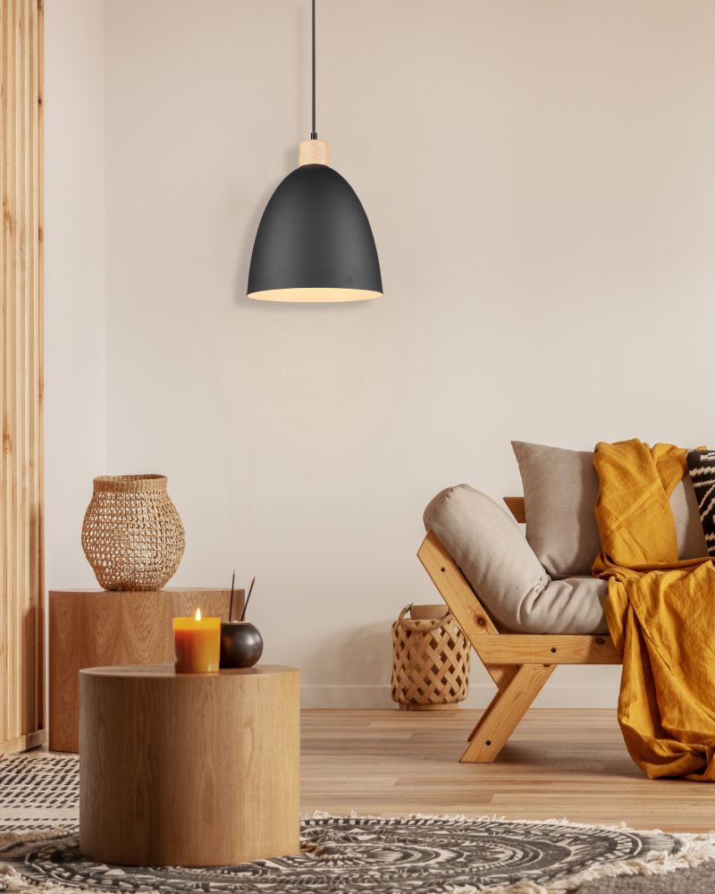 Scandinavian sofa with pillows and dark yellow blanket in bright living room interior with black chandelier